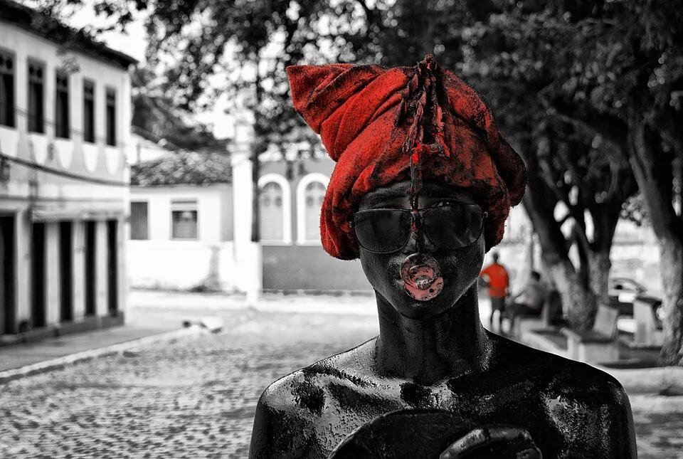 Integrante da manifestação Lambe-Sujo, com corpo pintado e turbante vermelho, em rua histórica de Laranjeiras